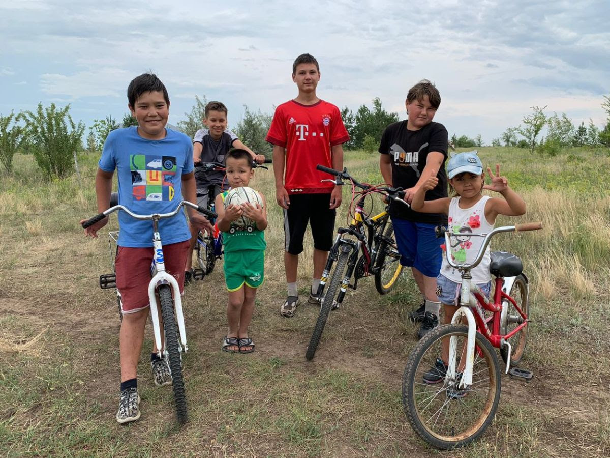 Many children are participating in bicycle races along the paths of the settlement